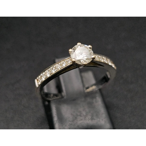 188 - An 18 K white gold ring with a brilliant cut diamond and more diamonds on the shoulders of the ring.... 