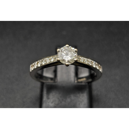 188 - An 18 K white gold ring with a brilliant cut diamond and more diamonds on the shoulders of the ring.... 