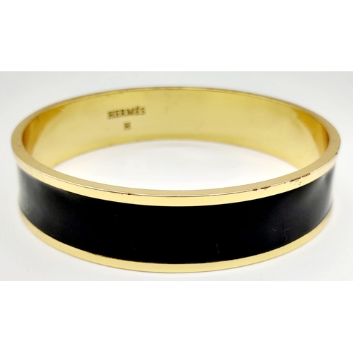 325 - A Hermes Gold Plated Bangle. Logo on inner and outer black enamel. 6.5cm inner diameter.