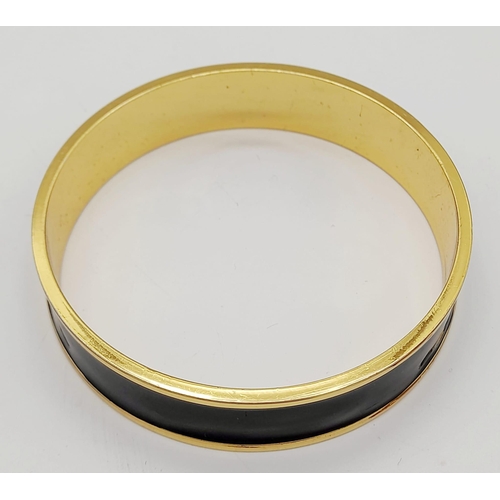 325 - A Hermes Gold Plated Bangle. Logo on inner and outer black enamel. 6.5cm inner diameter.