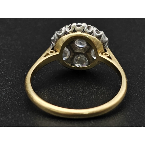 289 - An 18K Yellow Gold and Platinum Diamond Ring. Seven near white diamonds create the perfect flower. 1... 