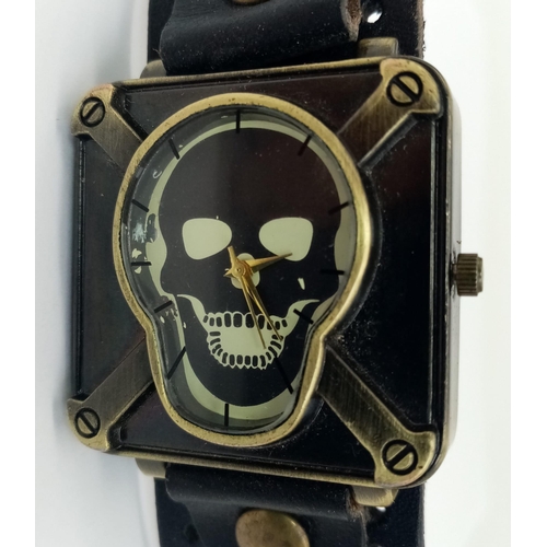 978 - A SKULL WATCH ON A BLACK LEATHER MILITARY STYLE STRAP, AND A SKELETON HAND LEATHER STUDDED BRACELET.... 