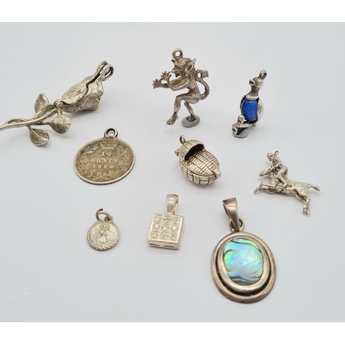 527 - A Small Collection of Nine Silver Charms or Pendants Including: Rose, book, cot, St Christopher, cow... 