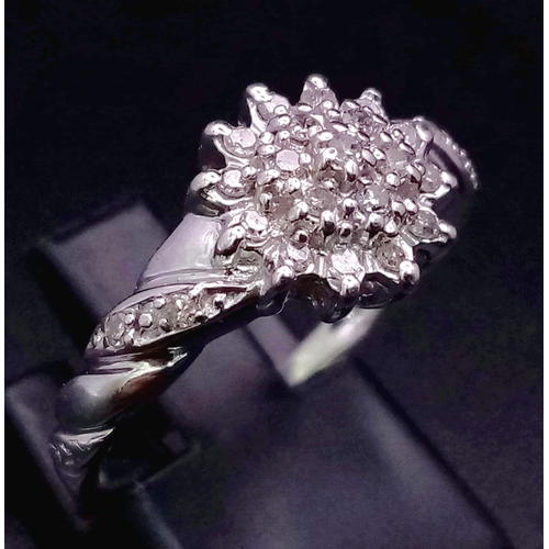 654 - 9k white gold diamond cluster ring with twist shoulders. 0.20ct Diamond. Total Weight 2.7g, size M