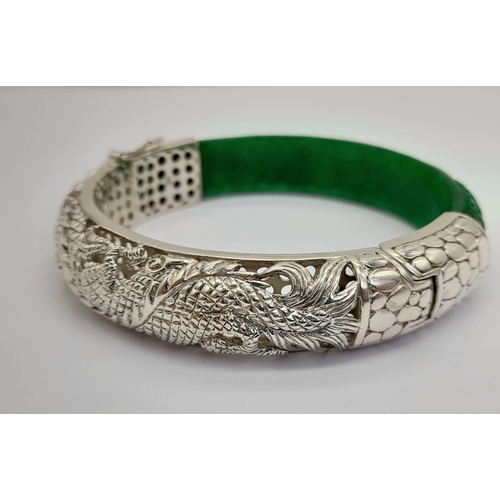 146 - A quality sterling silver and carved green jade bangle with a Chinese dragon. In excellent/unused co... 