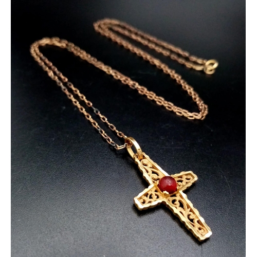 181 - A vintage, 18 K yellow gold intricately carved cross with a ruby cabochon, on a gold chain. Cross di... 