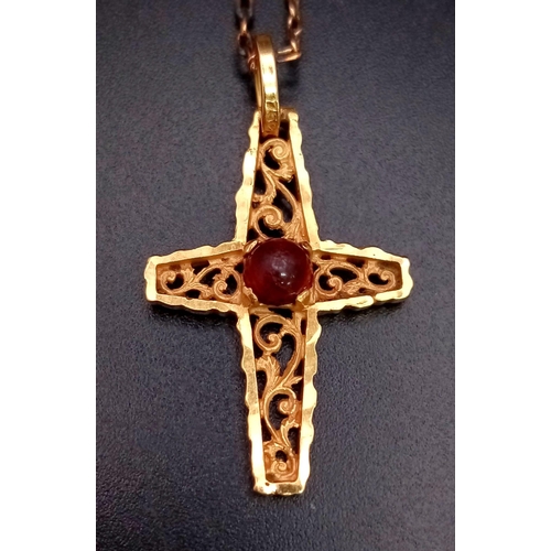 181 - A vintage, 18 K yellow gold intricately carved cross with a ruby cabochon, on a gold chain. Cross di... 