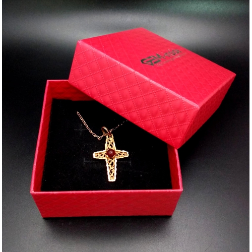 181 - A vintage, 18 K yellow gold intricately carved cross with a ruby cabochon, on a gold chain. Cross di... 