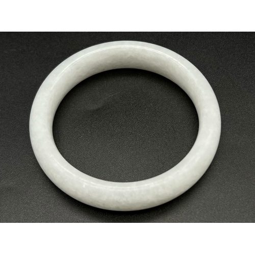 956 - A Chinese White Jade Bangle. 56mm inner diameter. 16mm width.