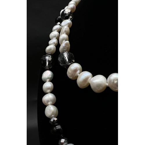 451 - A Cultured Freshwater Pearl and Onyx Rope Length Necklace. 110cm