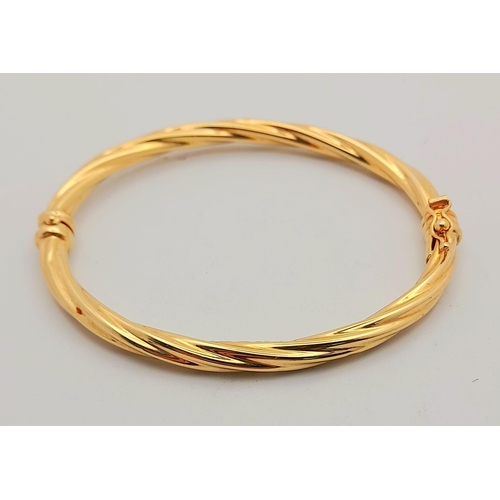 25 - A 9K Yellow Gold Bangle with Twist Decoration and Clip-Clasp. 5cm inner diameter. 4.67g