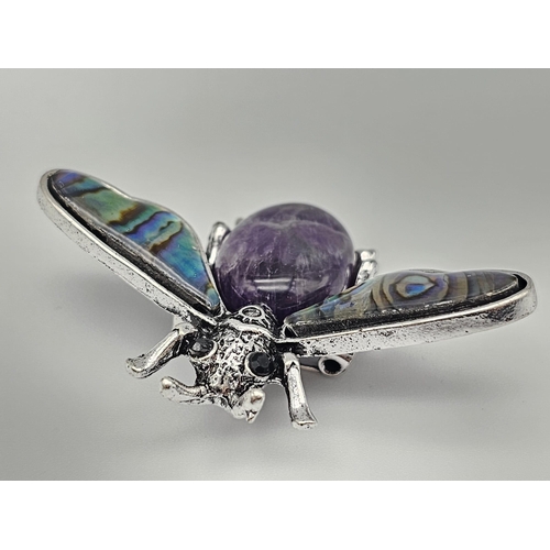 444 - An Amethyst Bee Brooch with Decorative Shell Wings. Wingspan - 5cm. On white metal.