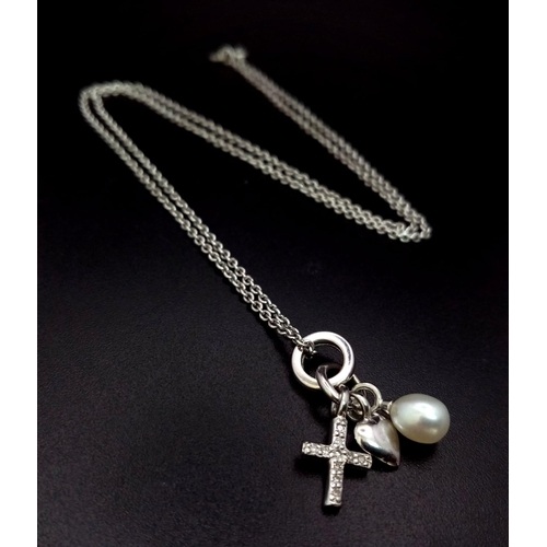 634 - A 9K WHITE GOLD PENDANT WITH A PEARL , HEART AND A CROSS CHARM ON A 40cms chain .   4.5gms    ref 90... 