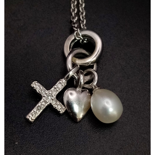 634 - A 9K WHITE GOLD PENDANT WITH A PEARL , HEART AND A CROSS CHARM ON A 40cms chain .   4.5gms    ref 90... 