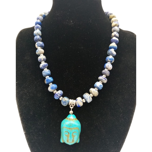 231 - A lapis lazuli necklace with a turquoise Buddha head pendant, accompanied by matching earrings. Neck... 