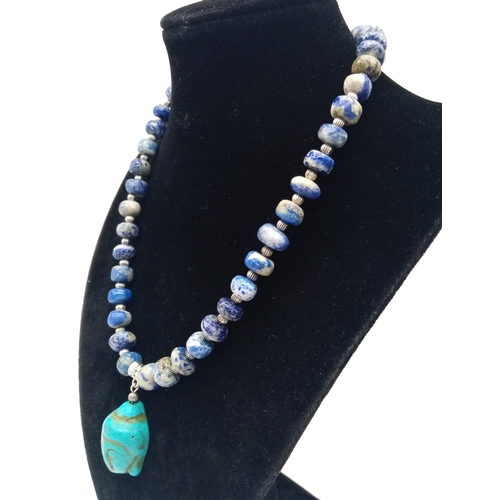 231 - A lapis lazuli necklace with a turquoise Buddha head pendant, accompanied by matching earrings. Neck... 
