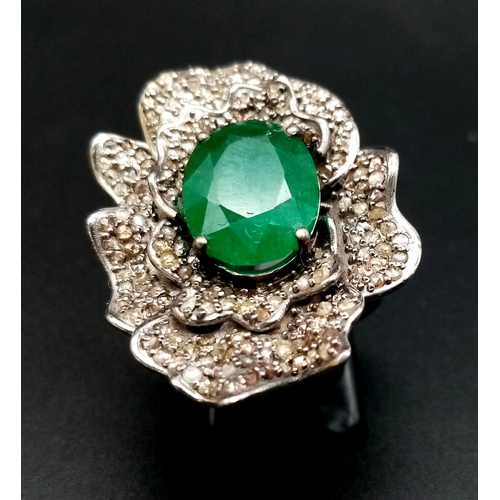 398 - A 6ct Oval Cut Emerald Gemstone Ring with 2.20ct of Diamond Floral Accents. Set in 925 Silver. Size ... 