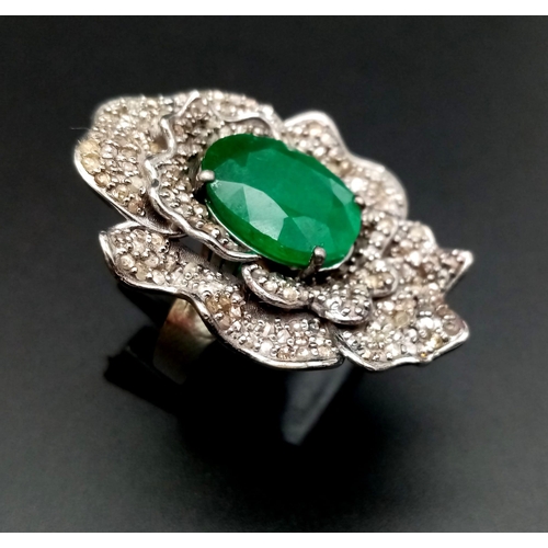 398 - A 6ct Oval Cut Emerald Gemstone Ring with 2.20ct of Diamond Floral Accents. Set in 925 Silver. Size ... 