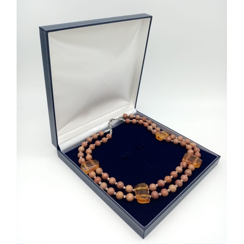 175 - A rare combination of fossil wood beads and amber, a two strand necklace in a presentation box. Leng... 