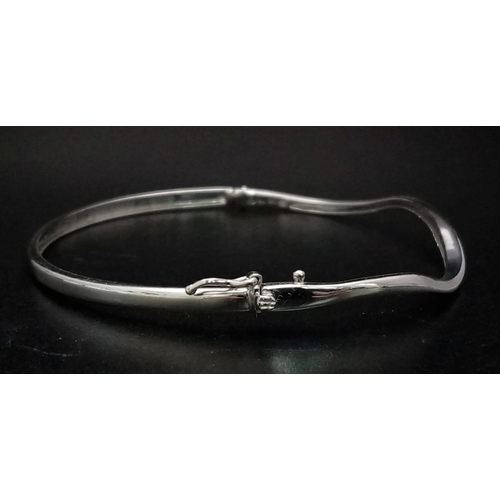 198 - A 9K White Gold and Diamond Wave Bangle. 6cmm inner diameter. Clip open clasp. 10 diamond wave. 5.69... 