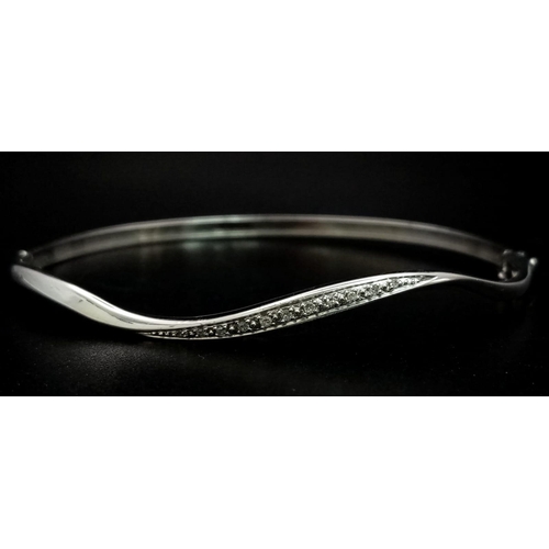 198 - A 9K White Gold and Diamond Wave Bangle. 6cmm inner diameter. Clip open clasp. 10 diamond wave. 5.69... 