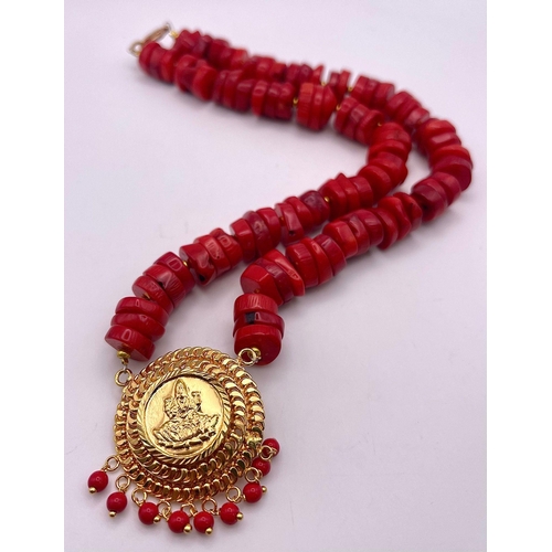 478 - A Red Rondelle Bead Coral Necklace with a Lakshmi Gilded Pendant - 4cm. Necklace - 42cm.