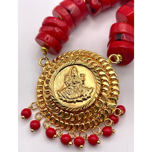 478 - A Red Rondelle Bead Coral Necklace with a Lakshmi Gilded Pendant - 4cm. Necklace - 42cm.