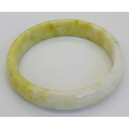 479 - A Soft Coloured Green and White Jade Bangle. 6cm inner diameter. 15mm width