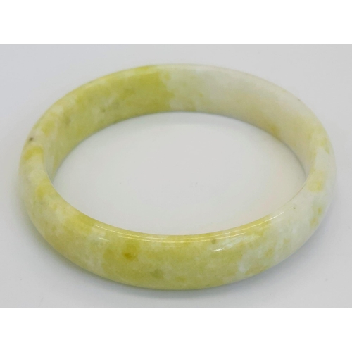 479 - A Soft Coloured Green and White Jade Bangle. 6cm inner diameter. 15mm width