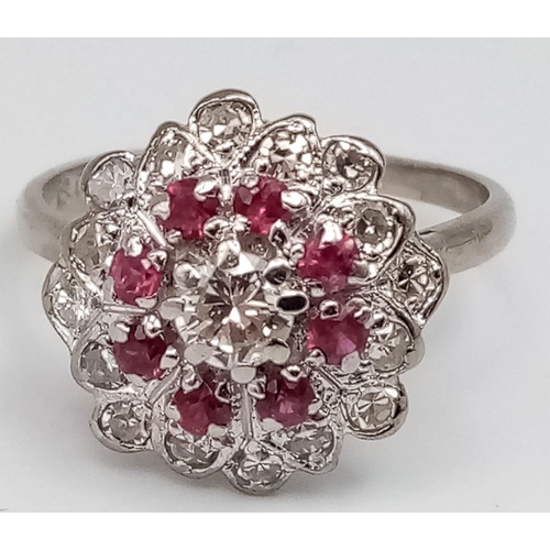 229 - 18K WHITE GOLD DIAMOND & RUBY CLUSTER RING.  0.35CT DIAMOND. TOTAL WEIGHT 3.8G.  SIZE N