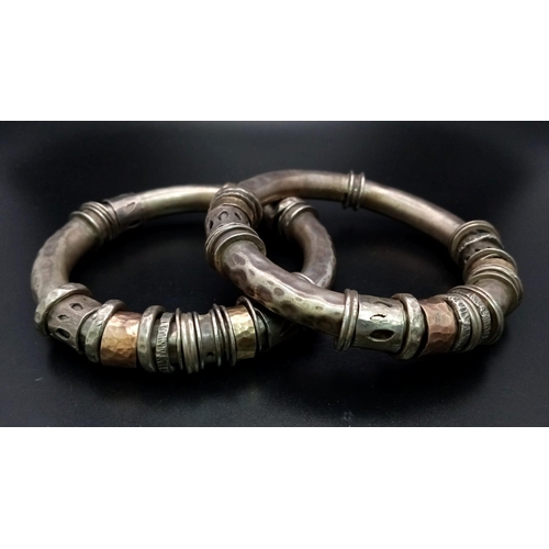 73 - A pair of silver and gold bangles in tubular form with loose ring decoration. The bangles have a pie... 