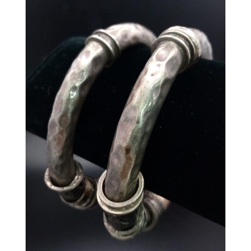 73 - A pair of silver and gold bangles in tubular form with loose ring decoration. The bangles have a pie... 