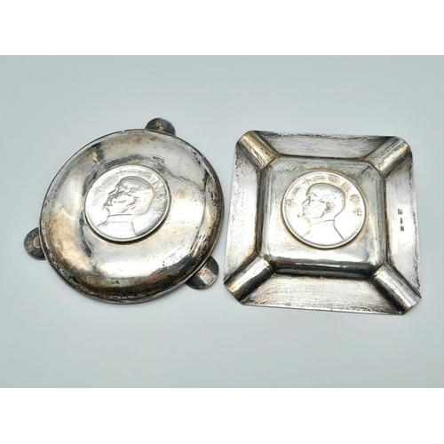 211 - 2 CHINESE SILVER VINTAGE ASH TRAYS WITH COINS EMBEDDED IN THE BASE.    160gms