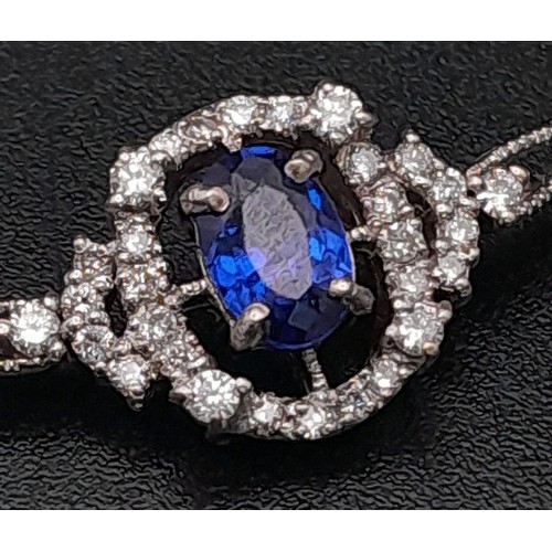 361 - An 18K White Gold, Diamond and Sapphire Bracelet. A central quality, clean sapphire surrounded by a ... 