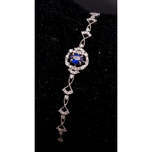 361 - An 18K White Gold, Diamond and Sapphire Bracelet. A central quality, clean sapphire surrounded by a ... 