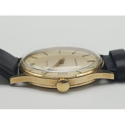 276 - A Vintage 9K Gold Garrard Gents Quartz Watch. Black leather strap. 9K Gold case - 34mm. Cream dial w... 