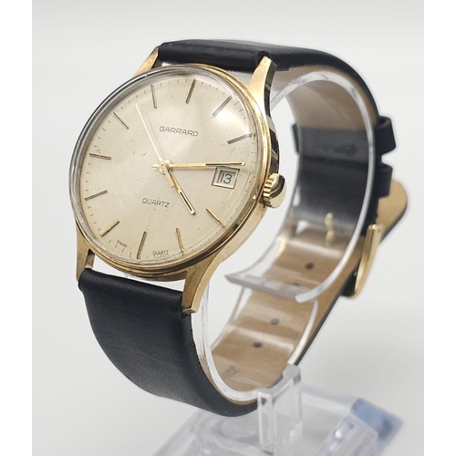 276 - A Vintage 9K Gold Garrard Gents Quartz Watch. Black leather strap. 9K Gold case - 34mm. Cream dial w... 