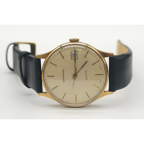 276 - A Vintage 9K Gold Garrard Gents Quartz Watch. Black leather strap. 9K Gold case - 34mm. Cream dial w... 