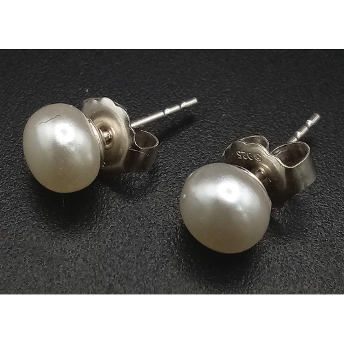 1748 - A PAIR OF SMALL PEARL STUD EARRINGS SET IN SILVER .  .55gms