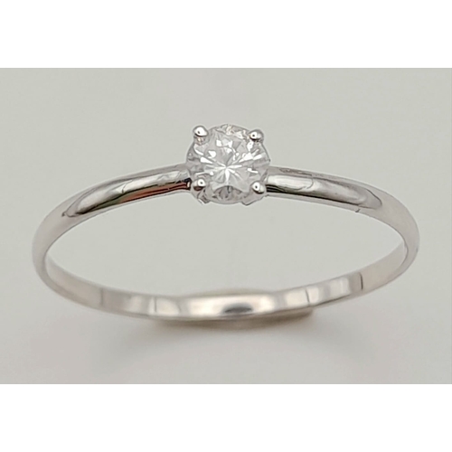 472 - A DAINTY 14K WHITE GOLD DIAMOND SOLITAIRE RING .   .75grm   size O/P