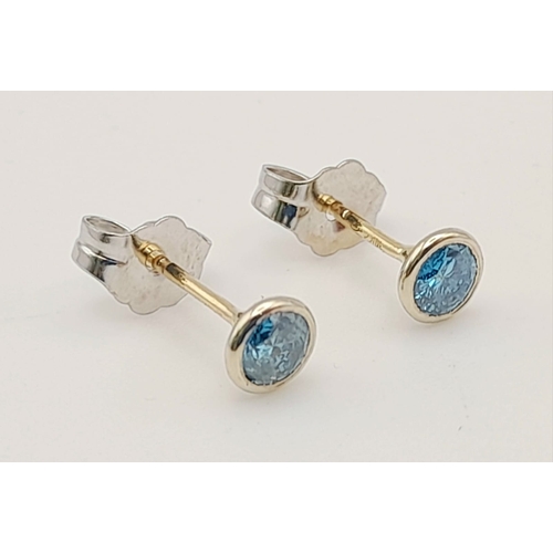 479 - A PAIR OF 14K WHITE GOLD BLUE DIAMOND SMALL STUD EARRINGS .   .6grm