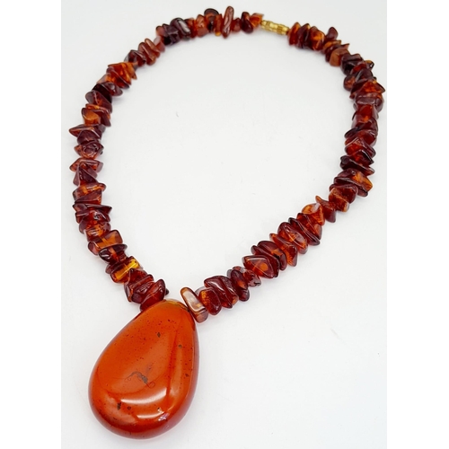 203 - A Baltic amber necklace with a large (55 x 37 x 15 mm) pear shaped cabochon pendant with organic deb... 