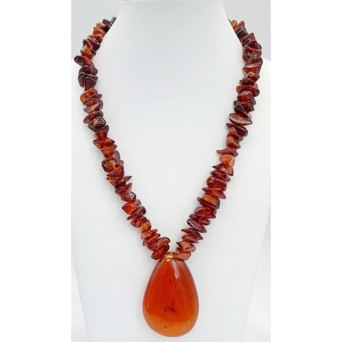 203 - A Baltic amber necklace with a large (55 x 37 x 15 mm) pear shaped cabochon pendant with organic deb... 