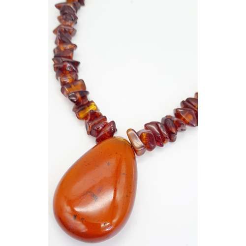 203 - A Baltic amber necklace with a large (55 x 37 x 15 mm) pear shaped cabochon pendant with organic deb... 