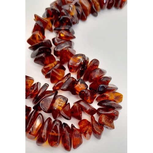 203 - A Baltic amber necklace with a large (55 x 37 x 15 mm) pear shaped cabochon pendant with organic deb... 