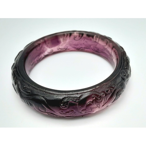 154 - A rare, vintage, amethyst coloured PEKING GLASS bangle with carved hunting scene of dogs and mythica... 