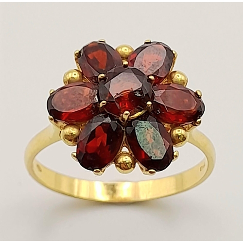 266 - A 18K YELLOW GOLD GARNET RING IN FLORAL DESIGN. TOTAL WEIGHT 4.8G. SIZE S.