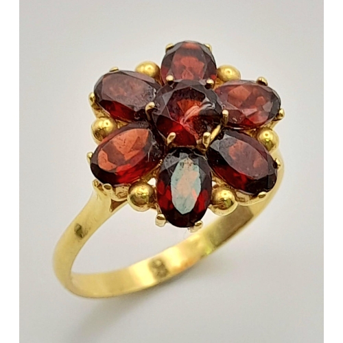 266 - A 18K YELLOW GOLD GARNET RING IN FLORAL DESIGN. TOTAL WEIGHT 4.8G. SIZE S.