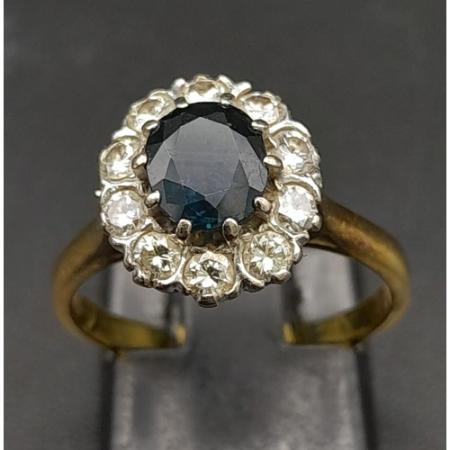 156 - An 18K Yellow Gold Diamond and Sapphire Ring. Central oval sapphire surrounded by a halo of diamonds... 