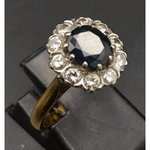 156 - An 18K Yellow Gold Diamond and Sapphire Ring. Central oval sapphire surrounded by a halo of diamonds... 